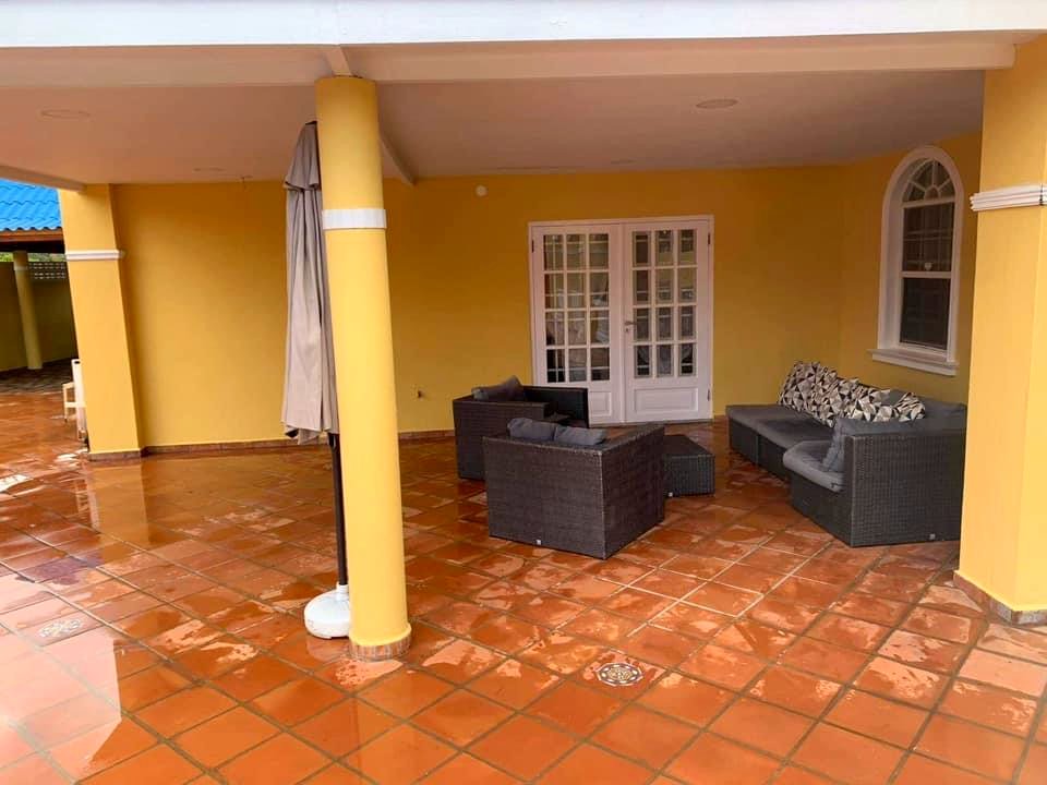 A covered terrace beside the pool with wicker sofas