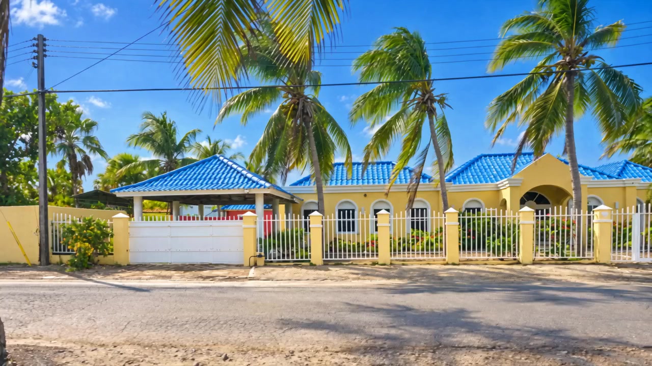 The front of Villa Rosa Carmen from the street, with blue roofs and coconut palms